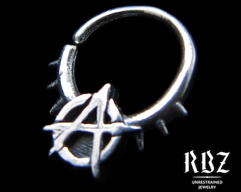 May include: A silver hoop ring featuring a prominent anarchy symbol charm and small spikes along the outer edge. The text "RBZ UNRESTRAINED JEWELRY" is visible in the corner, along with social media icons and the text "Solid Sterling silver".