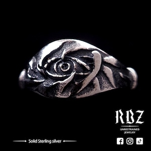 May include: A silver ring with a detailed design of a swirling eye. The ring is made of solid sterling silver.