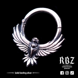 May include: A silver hoop earring with a detailed, stylized bird design. The bird has outstretched wings and a detailed head. The hoop is made of solid sterling silver.