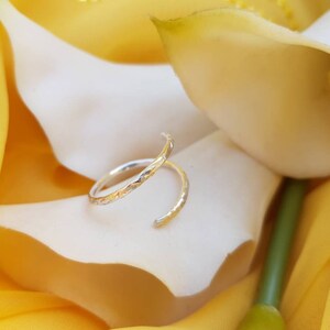 May include: A silver ring with a textured design. The ring is twisted and has a delicate, minimalist style.