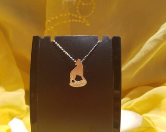 May include: A silver chain necklace with a gold wolf pendant. The pendant is a silhouette of a wolf standing on its hind legs. The necklace is displayed on a black stand.