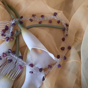 May include: Two silver hair combs adorned with purple gemstone beads and a delicate silver chain with purple gemstone beads. The combs and chain are displayed on a beige fabric background.
