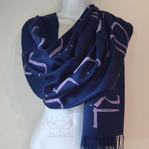 May include: A navy blue scarf with a light purple geometric pattern. The scarf has a fringe on the bottom edge.