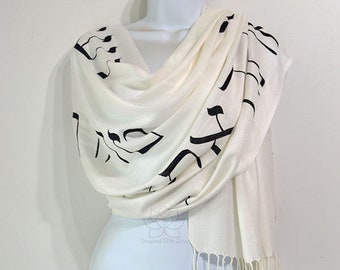 May include: White scarf with black Hebrew lettering. The scarf is made of a soft, lightweight fabric and has a fringed edge.