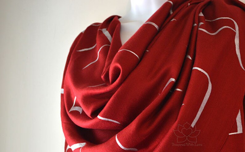 May include: A red scarf with a white abstract design. The scarf is made of a soft, lightweight fabric and is perfect for adding a touch of style to any outfit.
