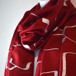 May include: A red scarf with a white geometric pattern. The scarf is made of a soft, warm material and is perfect for keeping you warm in the winter.