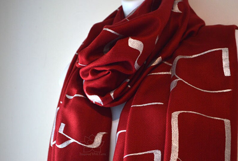 May include: A red scarf with a white geometric pattern. The scarf is made of a soft, warm material and is perfect for keeping you warm in the winter.