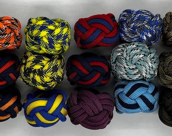 Puede incluir: Una colección de 20 gemelos de cuerda trenzada de colores. Los gemelos están hechos de varios colores y patrones, incluyendo rojo, azul, verde, amarillo y negro.