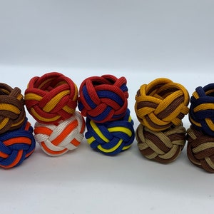 Puede incluir: Ocho anillos de cuerda trenzada de colores, cada uno con una combinaci&oacute;n de colores diferente. Los anillos est&aacute;n hechos de cuerda marr&oacute;n, roja, azul, amarilla, naranja y blanca.