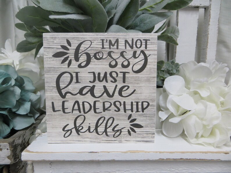 May include: A white wooden sign with a gray distressed finish. The sign reads "I'm not bossy I just have leadership skills".