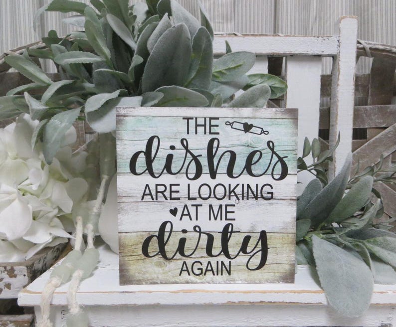 May include: A rustic wooden sign with a distressed whitewash finish. The sign features a teal and white background with the text "The dishes are looking at me dirty again".