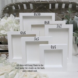 May include: A collection of white, square picture frames in various sizes, including 4x4, 5x5, 5x7, 6x6, 8x8, and 8x10 inches. The frames are arranged in a layered display, with text indicating each size. The text states that all sizes will hang flush to the wall.