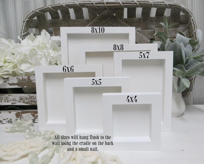 May include: A collection of white, square picture frames in various sizes, including 4x4, 5x5, 5x7, 6x6, 8x8, and 8x10 inches. The frames are arranged in a layered display, with text indicating each size. The text states that all sizes will hang flush to the wall.