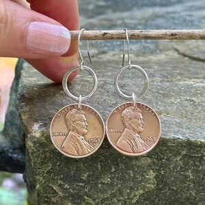 May include: A pair of silver hoop earrings with a 1963 US penny attached to each hoop. The pennies are copper colored and feature the profile of Abraham Lincoln.
