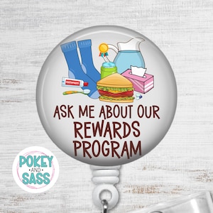 May include: A circular badge reel featuring a graphic of blue socks, a tube of toothpaste, a toothbrush, a green can, a blue pitcher, a sandwich, and a tissue box. The text reads ASK ME ABOUT OUR REWARDS PROGRAM in brown capital letters.