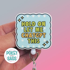 May include: A square badge reel with scalloped edges featuring a light blue background with white polka dots and four-pointed star accents. The text in bold yellow letters reads: HOLD ON LET ME CHATGPT THIS. The badge has a white plastic base and a metal clip.