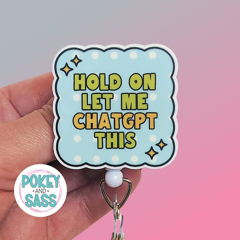 May include: A square badge reel with scalloped edges featuring a light blue background with white polka dots and four-pointed star accents. The text in bold yellow letters reads: HOLD ON LET ME CHATGPT THIS. The badge has a white plastic base and a metal clip.