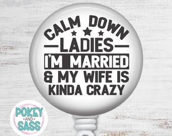 May include: A round white badge reel featuring black text that reads CALM DOWN LADIES I'M MARRIED & MY WIFE IS KINDA CRAZY with three small stars above the word LADIES. A small circular logo with the text POKEY AND SASS is visible in the corner.