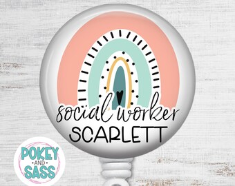 May include: A circular badge reel featuring a graphic of a rainbow in shades of peach, mint green, yellow, and dark blue with a small black heart. The text "social worker" and "SCARLETT" is printed in black lettering across the center of the design.