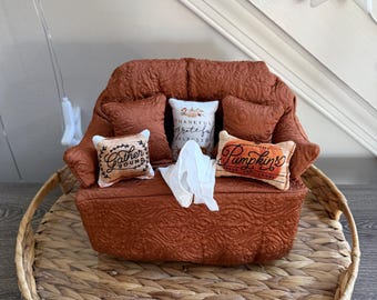 May include: A miniature rust-coloured quilted armchair featuring a textured floral pattern. It is decorated with three small accent pillows, one reading "Gather Round," one "Pumpkins," and one "Thankful grateful blessed," with a white tissue.