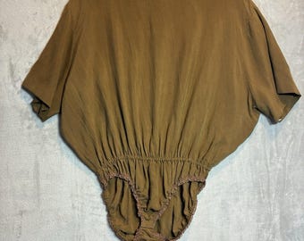 May include: A solid brown bodysuit featuring a wide boat neckline, short dolman sleeves, and an elasticised waistline. The bottom section includes high-cut leg openings finished with a delicate scalloped lace trim along the edges.