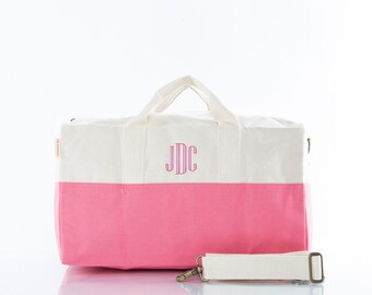 Può includere: Una borsa da viaggio in tela bianca e rosa con un monogramma rosa "JDC" sul davanti. La borsa ha una tracolla bianca.
