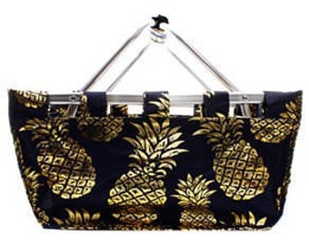 May include: A black fabric shopping basket with a gold pineapple pattern. The basket has a silver metal frame and handle. The basket is designed for carrying groceries or other items.