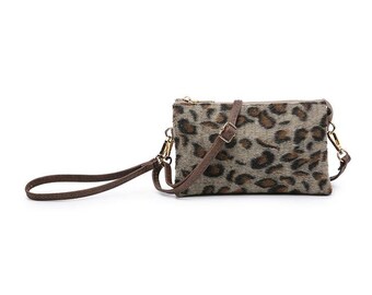 May include: A small brown faux fur crossbody bag with a leopard print pattern. The bag has a brown adjustable strap and a gold zipper.
