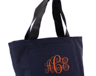May include: A navy blue insulated lunch bag with black handles and a monogrammed design in orange. The monogram is "ACE".