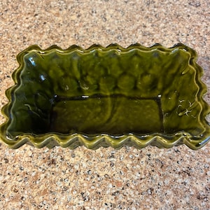 May include: A green ceramic baking dish with a scalloped edge. The dish is empty and ready to be used.