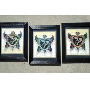 May include: Three framed prints of a stylized turtle with a Native American design. The turtles are in black, white, and shades of green, blue, and red. The frames are black.