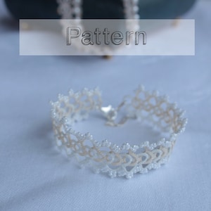 May include: A delicate white lace bracelet with a silver clasp. The bracelet is made with small white beads and has a delicate, intricate pattern.