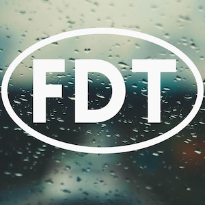 May include: A white oval sticker with the text "FDT" on a blurry background of raindrops on a window.