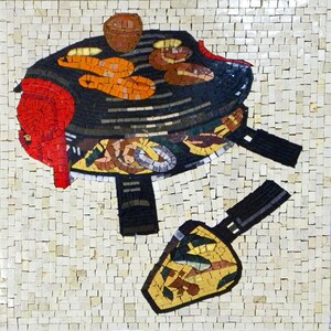 May include: A mosaic tile artwork depicting a black grill with red, orange, and brown food items on top. A black spatula with a yellow and green mosaic design is on the side.