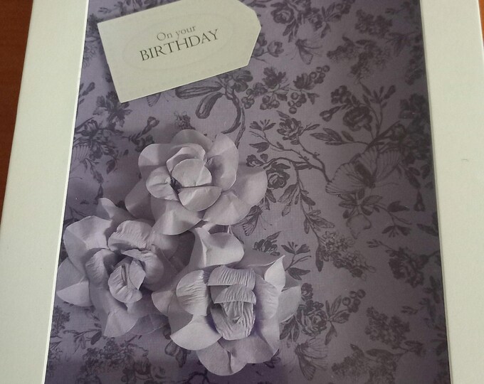 Handmade greetings card in a box, on your birthday . Lavender colour paper flowers on a lavender floral background.A5 card in box