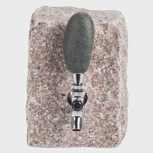 May include: A granite beer tap with a dark gray stone handle. The tap is made of polished chrome and is mounted on a rectangular block of pink and gray granite. The design is rustic and natural.