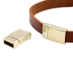 May include: Gold-toned magnetic clasp for leather bracelets. The clasp is made of metal and has a smooth, polished finish.