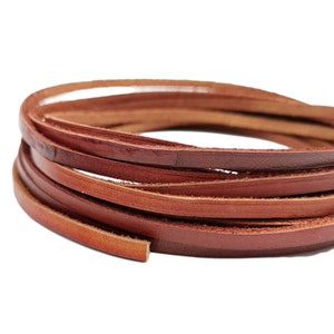 Può includere: Un primo piano di un rotolo di cordoncino in pelle marrone. Il cordoncino è largo circa 6 mm ed è realizzato in pelle morbida e flessibile.