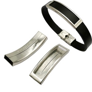 May include: A black leather bracelet with a stainless steel band and clasp. The band has a rectangular cutout for engraving. The bracelet is shown with two separate stainless steel pieces that are used to attach the band to the clasp.