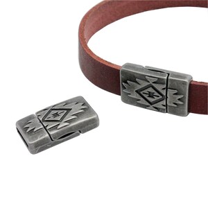 Peut inclure: Fermoir magnétique argenté avec un motif géométrique. Le fermoir est en métal et a une forme rectangulaire. Il est conçu pour être utilisé avec des bracelets en cuir.