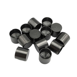 May include: A pile of black metal bottle caps. The caps have a ridged design on the top.