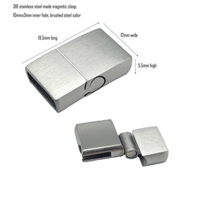 May include: A silver magnetic clasp for a watch strap or bracelet. It measures 1.95 inches long, 0.47 inches wide, and 0.22 inches high. The clasp has a brushed steel finish and a 0.39 inch by 0.12 inch inner hole.
