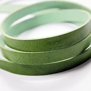 May include: Green leather cord, rolled up and ready for crafting projects. The leather is soft and supple, with a slightly textured surface.