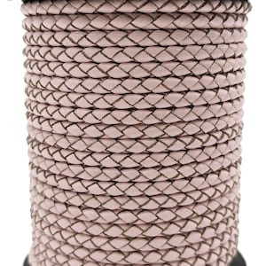 May include: A spool of pink braided leather cord. The cord is woven in a diamond pattern and is approximately 5mm wide.