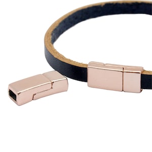May include: Two rose gold magnetic clasps for leather bracelets. The clasps are rectangular and have a smooth, polished finish.