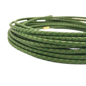 May include: A close-up of a green braided leather cord. The cord is coiled in a circle and is ready to be used for crafting projects.