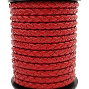 May include: A spool of vibrant red braided leather cord. The cord is tightly woven, creating a textured surface. The spool is dark, and the cord is wound neatly around it. This cord is suitable for various crafting projects.