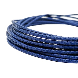 Può includere: Un cordoncino in pelle intrecciato blu. Il cordoncino è avvolto in un cerchio e ha una larghezza di circa 4 mm.