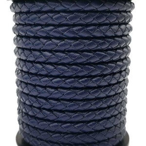May include: A spool of navy blue braided leather cord. The cord is tightly wound and has a smooth, polished finish.
