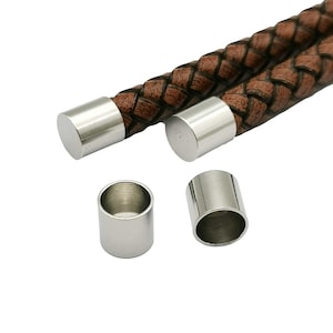May include: Four silver metal end caps for leather cord or bracelet. Two end caps are attached to brown leather cord.